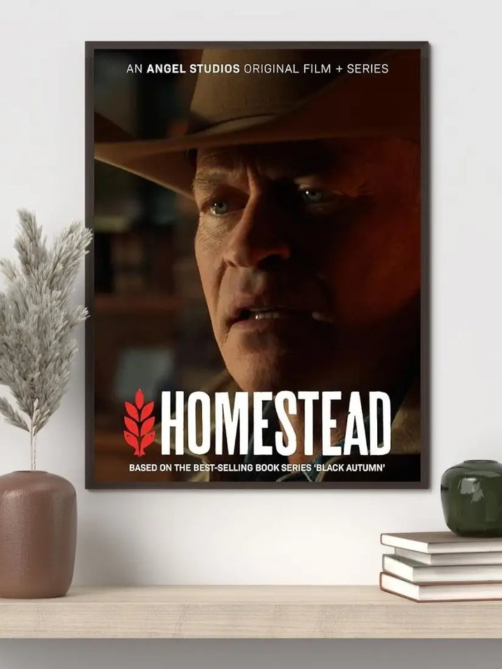 Homestead 2024 movie poster showing Jeff Eriksson and his family standing before the fortified mountain compound as smoke and distant destruction rise over a darkened horizon.